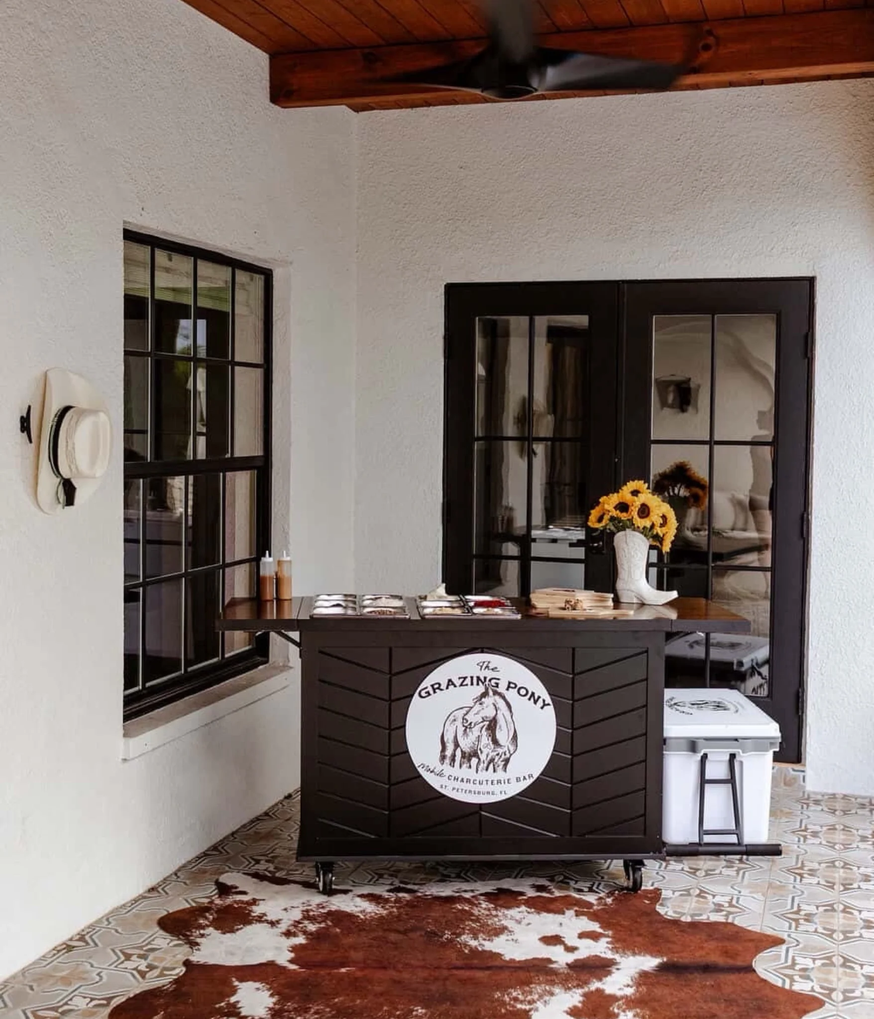 Black mobile charcuterie grazing bar set up on a covered patio for private events