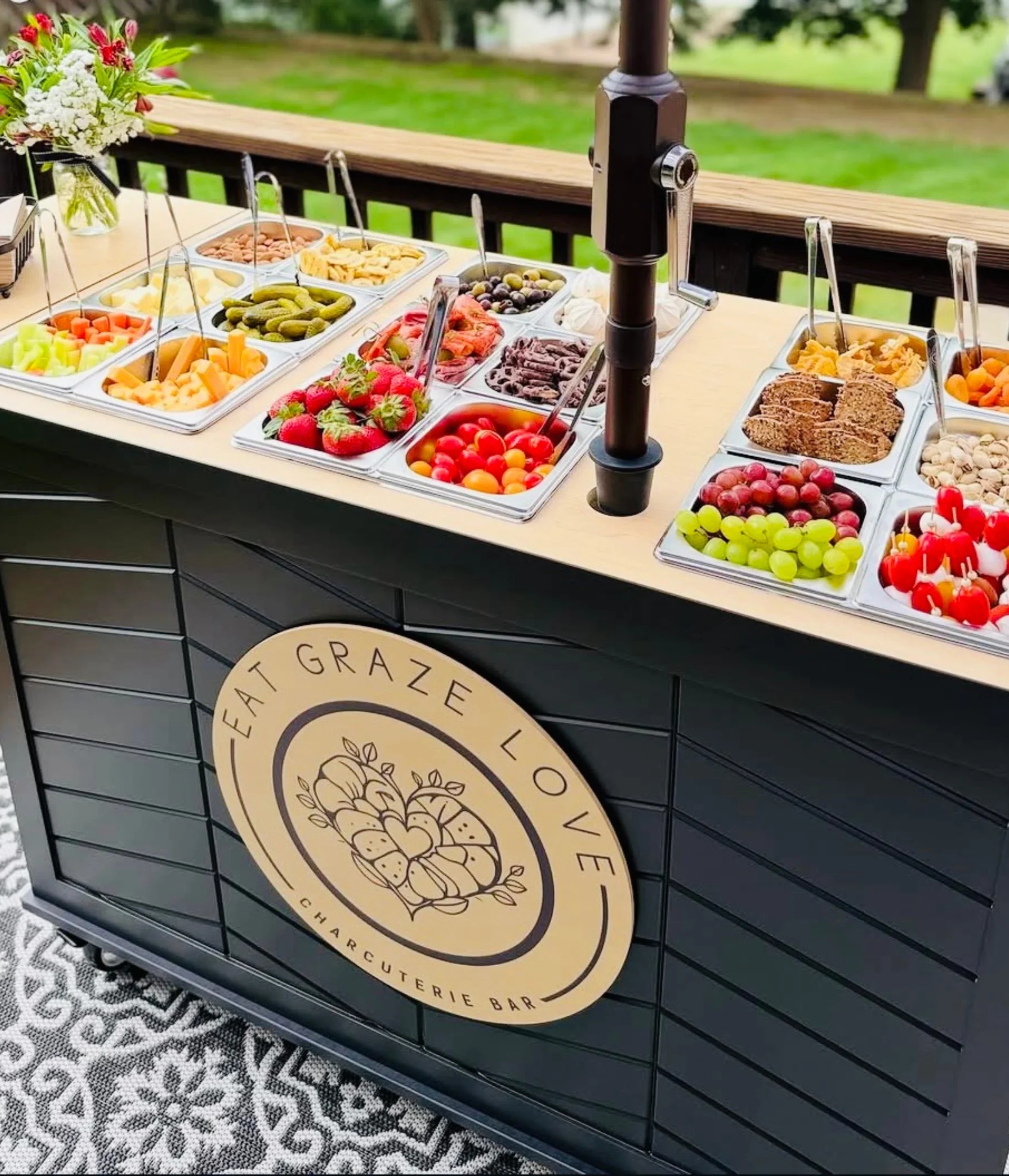 Mobile charcuterie grazing cart with fresh fruit, cheese, and snacks set up outdoors